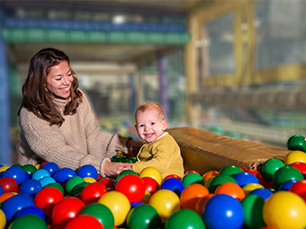 Mother and child using phone finder in ball pit